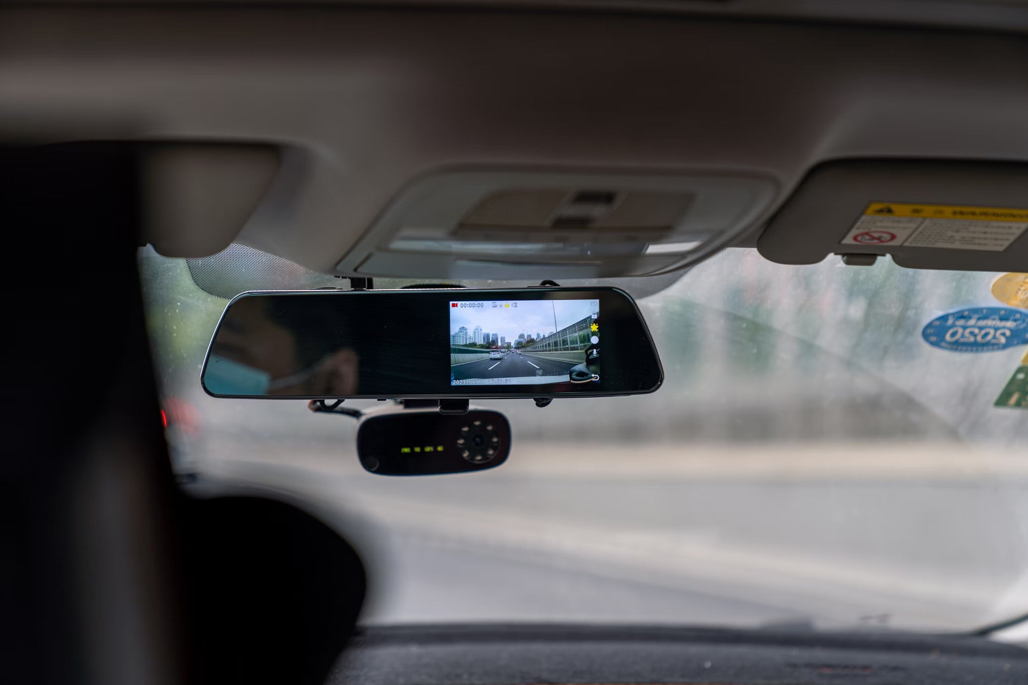 Mand med maske kører med dashcam i spejlet